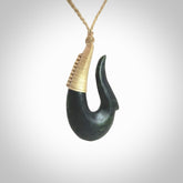 This photo shows a greenstone hook, or matau, pendant. It is a beautiful deep green jade. The cord is plaited oat coloured and the length can be adjusted.